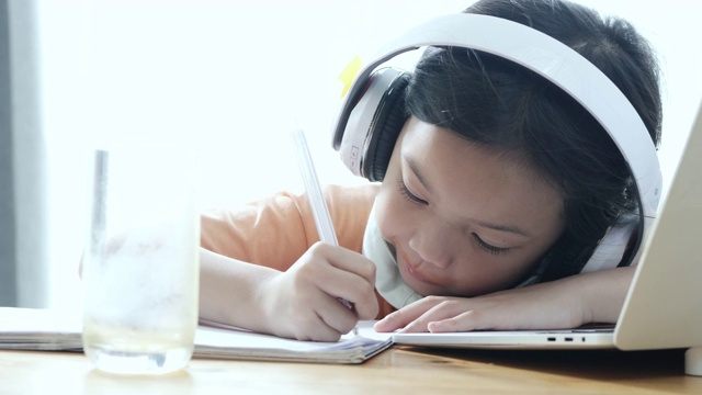 亚洲女孩喝着一杯橙汁，在家里学习新冠肺炎期间的电子学习，生活方式概念。视频下载