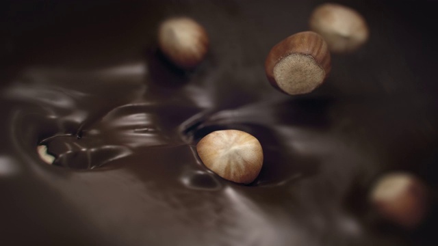 4K超级慢动作，榛子溅入液态黑巧克力视频素材