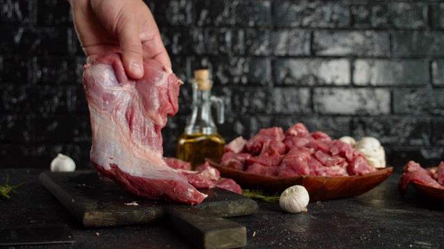 一个男人的手把一块生牛肉放在一块木板上。视频下载