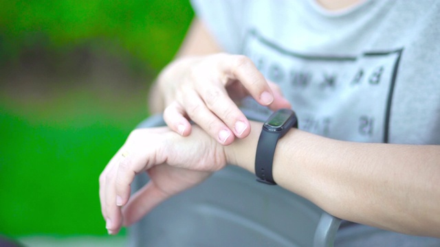 一名亚洲女性在公园使用智能手表视频素材