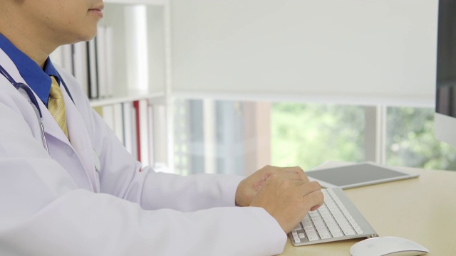 一段医生坐在办公室里用平板电脑打字的视频视频素材