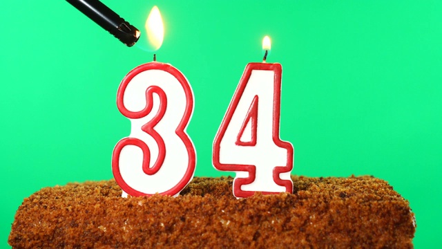 蛋糕上点着34号蜡烛。色度键。绿色的屏幕。孤立的视频下载