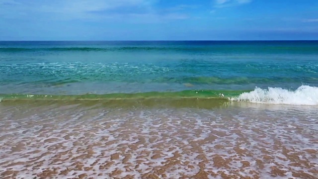 平静的海浪带着白色的泡沫冲击着异国情调的金色沙滩视频素材