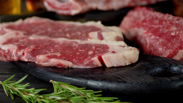 生的不同类型的肉在桌子上与迷迭香。视频素材