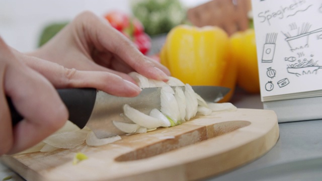 女厨师切新鲜的有机洋葱在木制砧板准备做沙拉和烹饪的特写。健康蔬菜和素食，家庭烹饪概念。视频素材