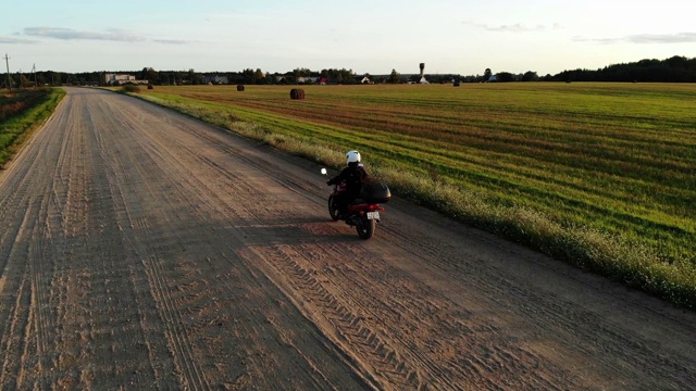 女人骑着摩托车在乡村公路上行驶，鼓舞人心的快乐自由爱好概念，从无人机上方的空中拍摄视频下载