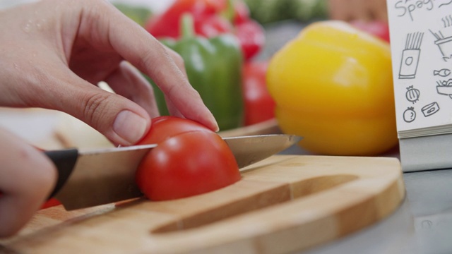 女厨师切新鲜的红色有机番茄在木制砧板准备做沙拉和烹饪的特写。健康蔬菜和素食，家庭烹饪概念。视频素材