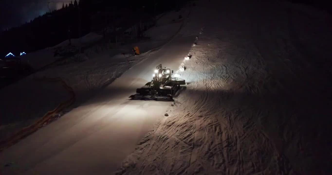 鸟瞰图。雪整理雪猫机器修复在晚上滑雪场斜坡上的小径。视频素材