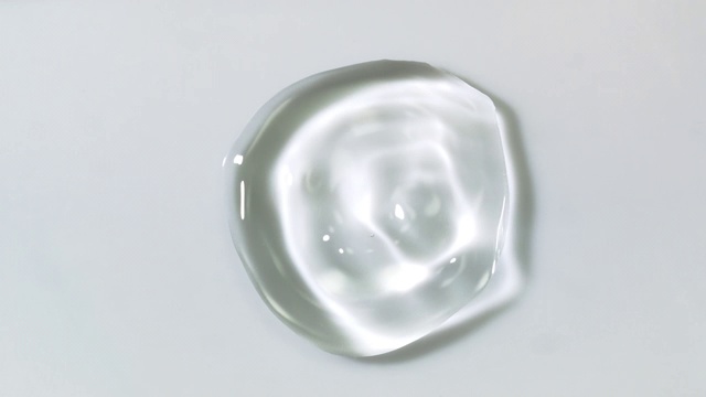 慢动作和超微距镜头的一个水晶清澈的水滴弹跳和移动在白色的表面视频素材