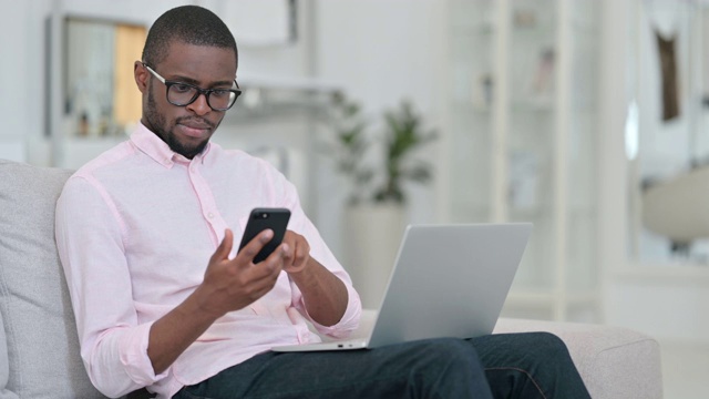 非洲人在家里使用智能手机和笔记本电脑视频素材