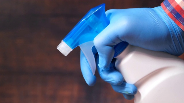 手持喷瓶的蓝色橡胶手套，擦拭平面视频下载