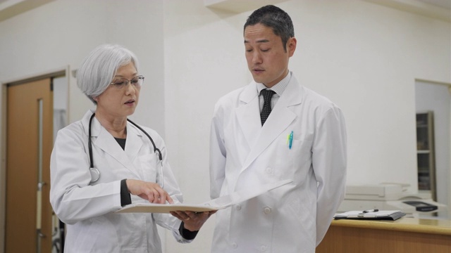 一名日本男医生与女护士交谈，并查看病人的档案视频素材