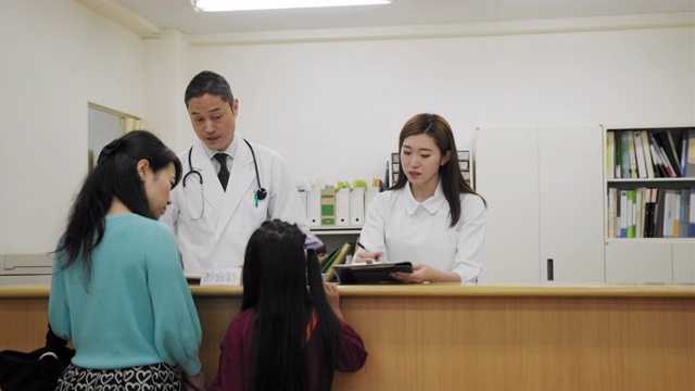一位成熟的日本妇女在医院挂号处与女护士交谈视频素材