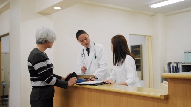 一位日本老妇人在医院挂号处与女护士交谈视频素材