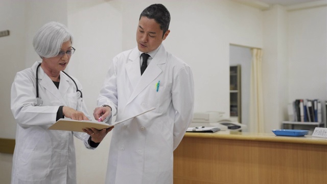 一名日本男医生与女护士交谈，并查看病人的档案视频素材