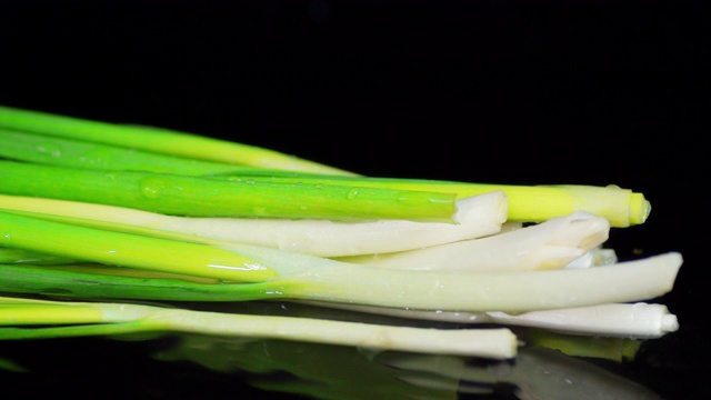 新鲜的绿洋葱躺在水面上。视频素材