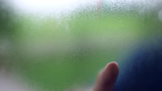 手用手指在蒸窗上画心，背景是绿色的稻田视频素材