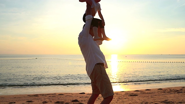 日出时，父亲和儿子站在海滩上，他们一起度过了宝贵的家庭时光。用慢镜头拍摄。视频素材