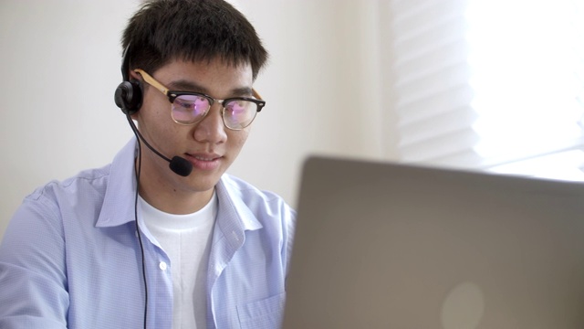 亚洲商人在家开会时戴上耳机在笔记本电脑上进行会议视频通话视频素材