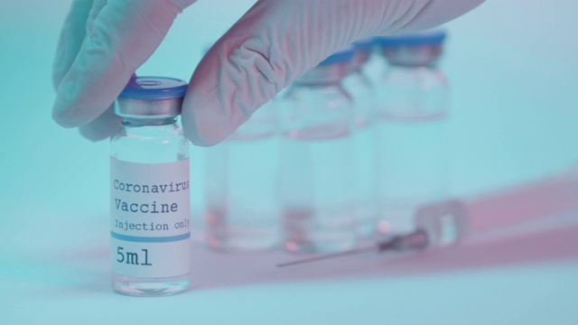 冠状病毒疫苗字母瓶附近的科学家在乳胶手套上蓝色视频下载