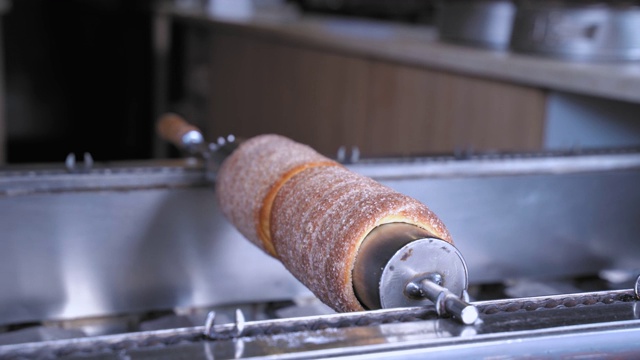 东欧传统糕点的制作过程是把擀好的面团裹在一根棍子上，烤一烤，上面撒上糖视频下载