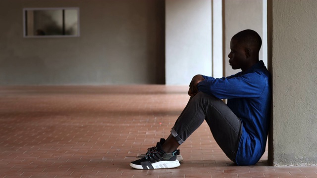 孤独、沮丧——一个沉思的年轻黑人靠在墙上视频下载