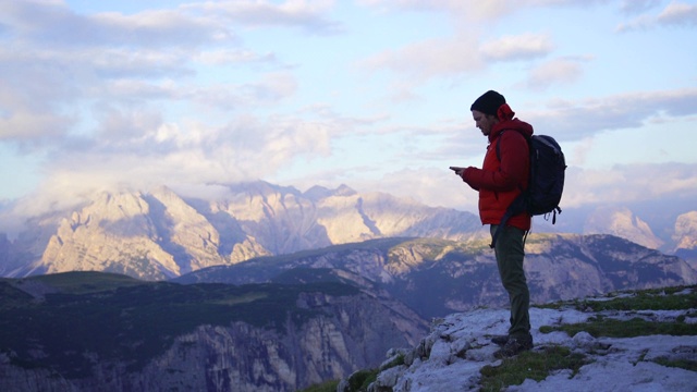 一名徒步旅行者在多洛米特山停下来时使用手机视频下载