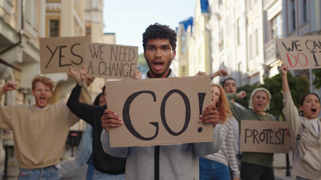 一名混合种族的男子在示威表演前张贴海报，抗议活动人士在背景视频素材
