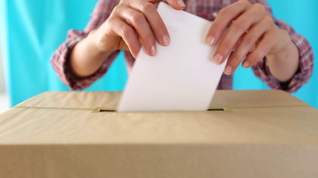 人们在投票站的投票箱里投一张纸选票。视频素材