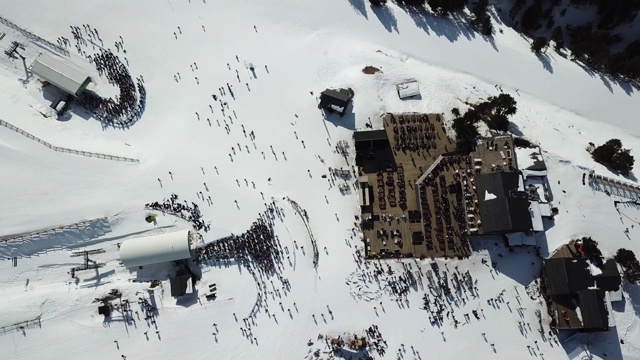 在安道尔的格兰德瓦利拉滑雪胜地沿着滑雪斜坡平稳移动的鸟瞰图。冬天的风景。山上餐厅的顶视图和滑雪缆车的长队视频下载