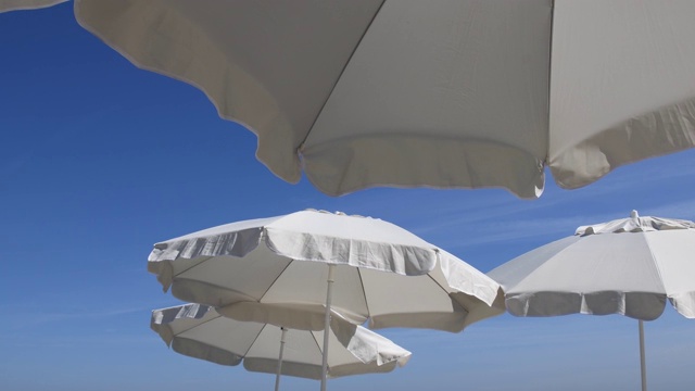 白色的沙滩伞映衬着蔚蓝的天空。旅游度假的象征视频下载