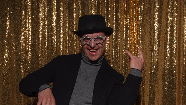 一名男子戴着帽子和派对眼镜在照相亭摆姿势拍照视频下载