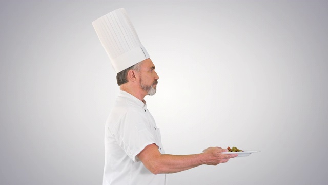 男厨师白色制服与一盘沙拉在梯度背景上运行视频下载