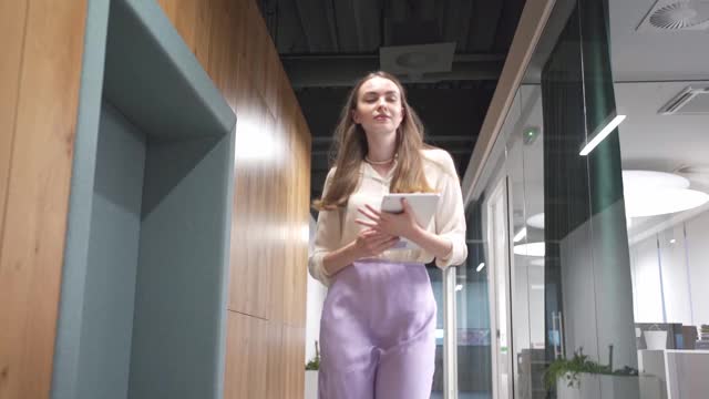 一位年轻美丽自信的女商人走过办公室的走廊视频下载