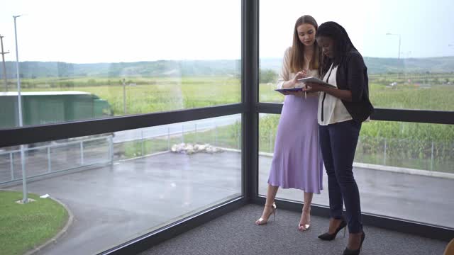 两个年轻的现代多民族商务女性在会议室讨论业务成果视频下载