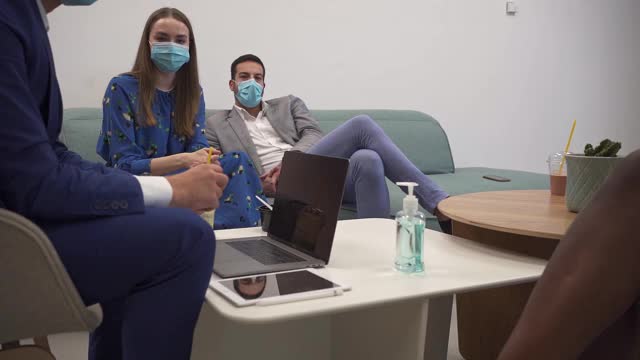 由于COVID-19病毒大流行，一名商人在公司午餐时间消毒双手，并戴上防护口罩视频下载