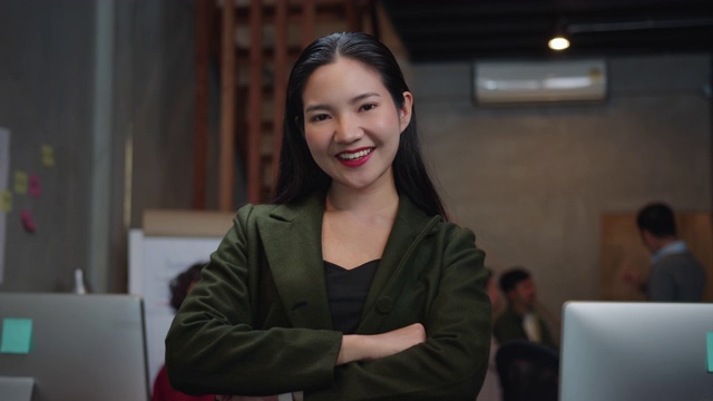 自信的亚洲女商人面带微笑，双臂交叉看着镜头，积极，满意，愉快的表情享受在现代办公室的成功摆姿势。视频素材