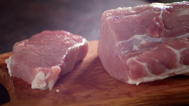 生的一块猪肉在砧板上慢慢旋转。视频下载