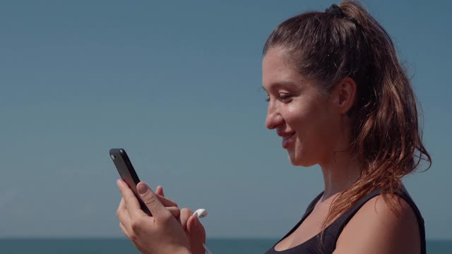 活泼的女人在慢跑前选择手机音乐视频下载