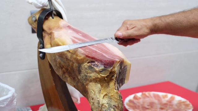 长者用火腿刀切伊比利亚火腿。西班牙美食的概念。视频下载