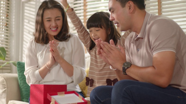 亚洲妈妈和爸爸给她可爱的小女儿一个惊喜给他们的孩子一个生日礼物。视频素材