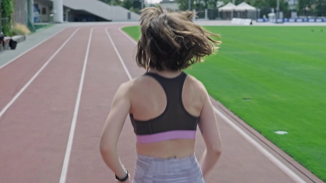 女孩在体育场慢跑。积极的生活方式。在体育场跑道上进行女子训练。视频下载