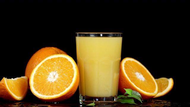 橙汁装在玻璃杯里，橙子切片慢慢旋转。视频下载