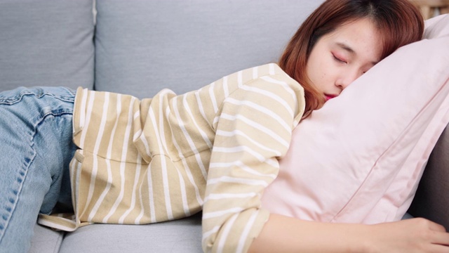 年轻困倦的亚洲女人在休闲衣服倒在沙发上感到疲惫和疲惫。视频素材