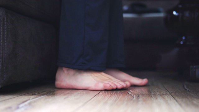 早上从床上起来。女性的脚踩在脚趾上，强化地板近视频下载