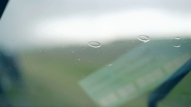 近景黑色金属雨刷清除挡风玻璃上的雨滴视频下载