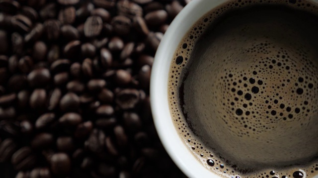 白杯的新鲜咖啡在烤咖啡豆的背景。视频素材