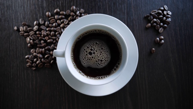 白杯的新鲜咖啡在烤咖啡豆的背景。视频素材