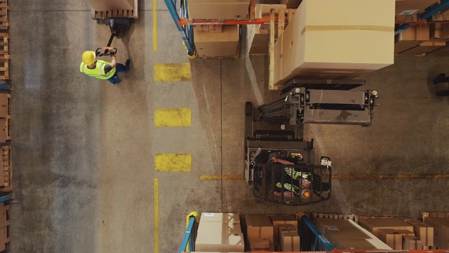 自上而下的无人机拍摄:电动叉车卡车操作员举起托盘与纸箱在一个大零售仓库的货架。物流产品和货物配送中心视频素材