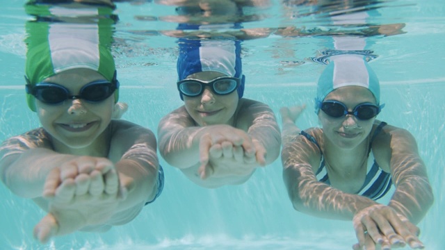 三个快乐的孩子在游泳池里游泳视频素材